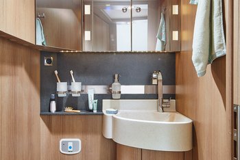 Detailaufnahme des Raumbads im Wohnmobil mit Blick auf das Waschbecken und den Spiegelschrank