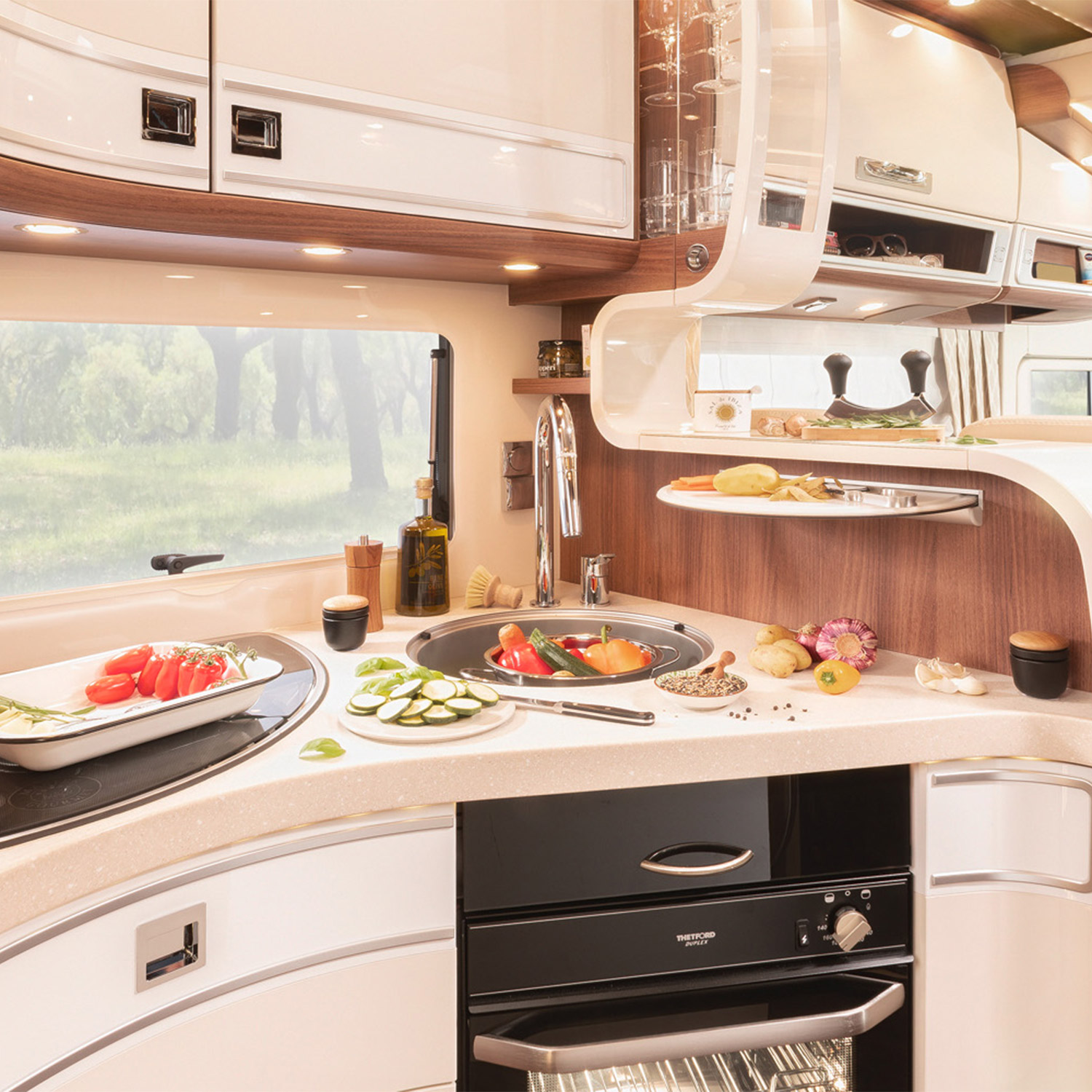 Übersicht der Küche eines Reisemobils mit hellen Fronten und integriertem Backofen