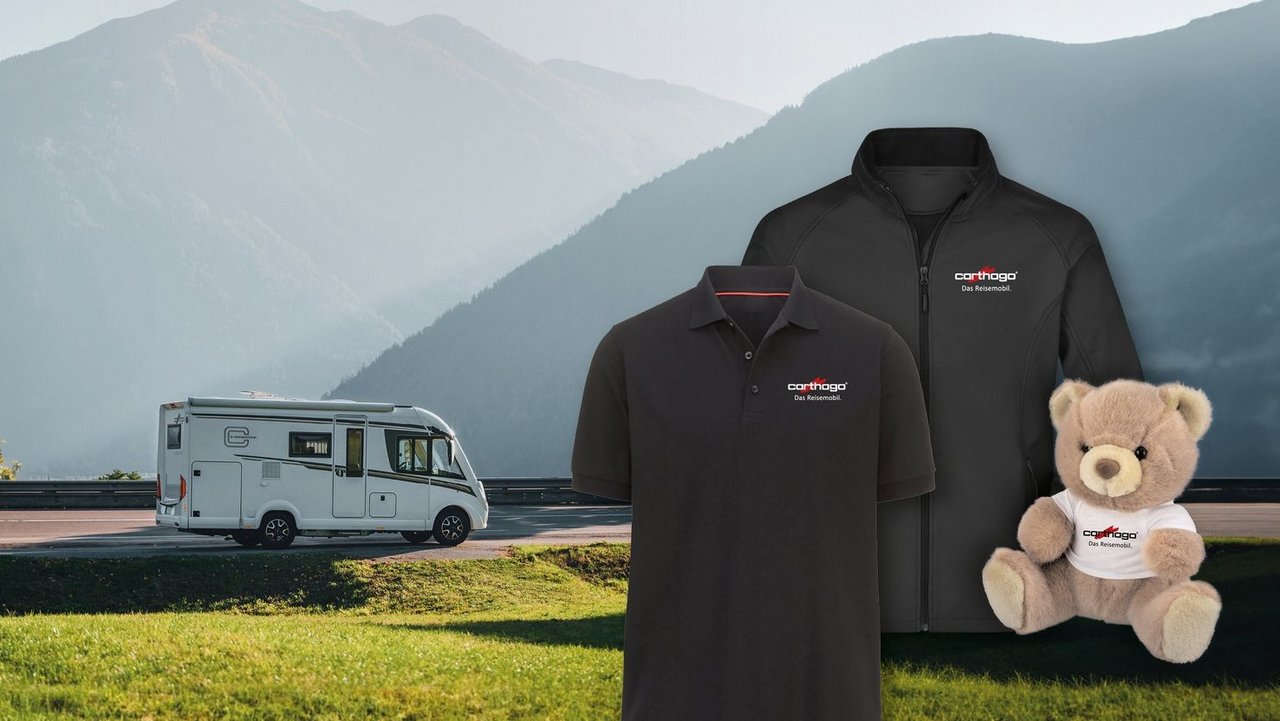 Carthago T-Shirt´s und Teddybär aus dem Webshop. Im Hintergrund Vollintegriertes Wohnmobil in Berglandschaft