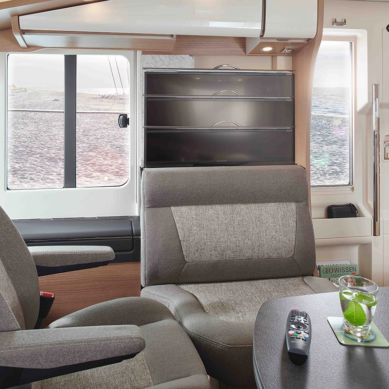 Carthago Sitzgruppe in grau mit TV-Auszugssystem und Blick auf einen Strand