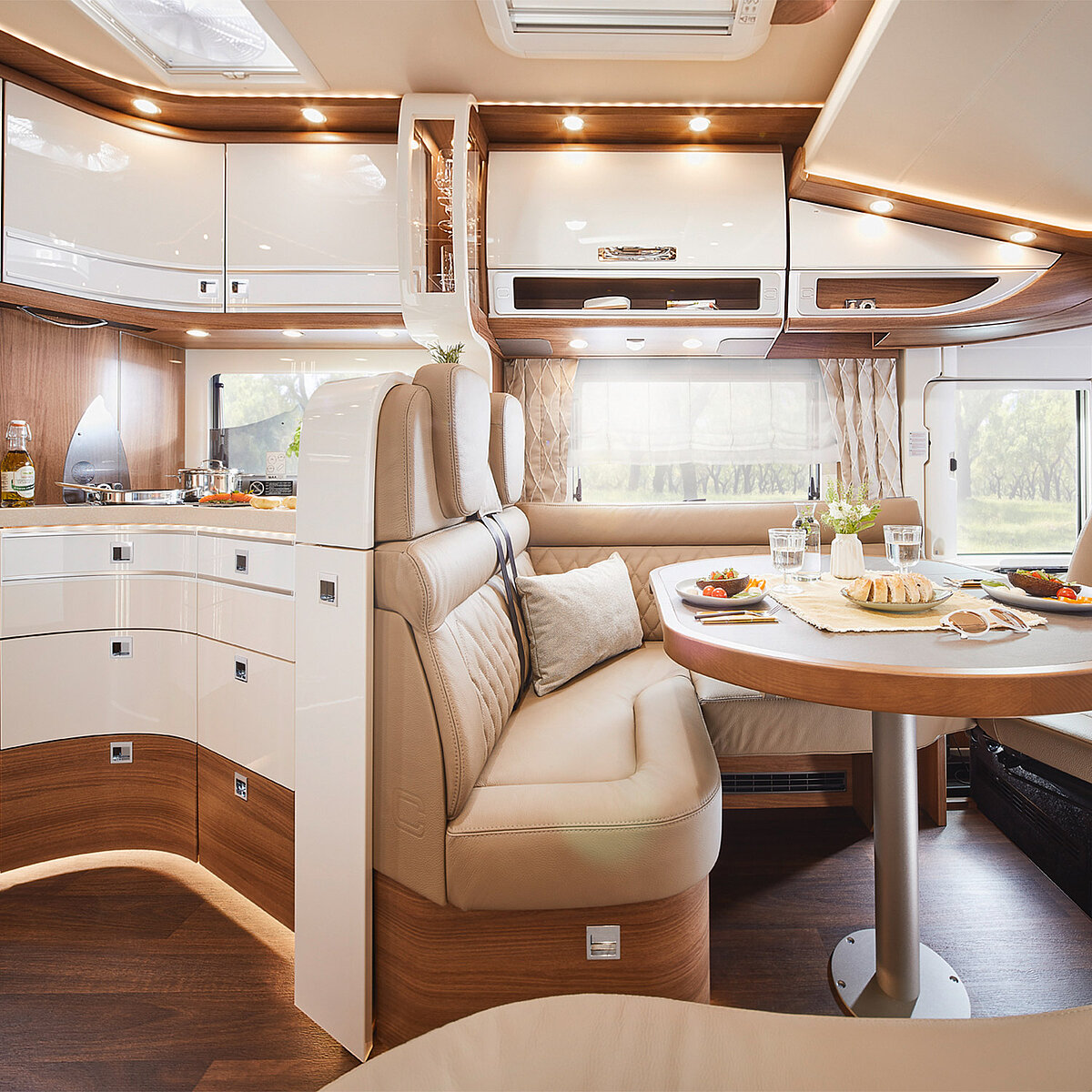 Ansicht des Sitzbereichs und der Küche eines Reisemobils mit Wohnraumtisch und Sitzbereich