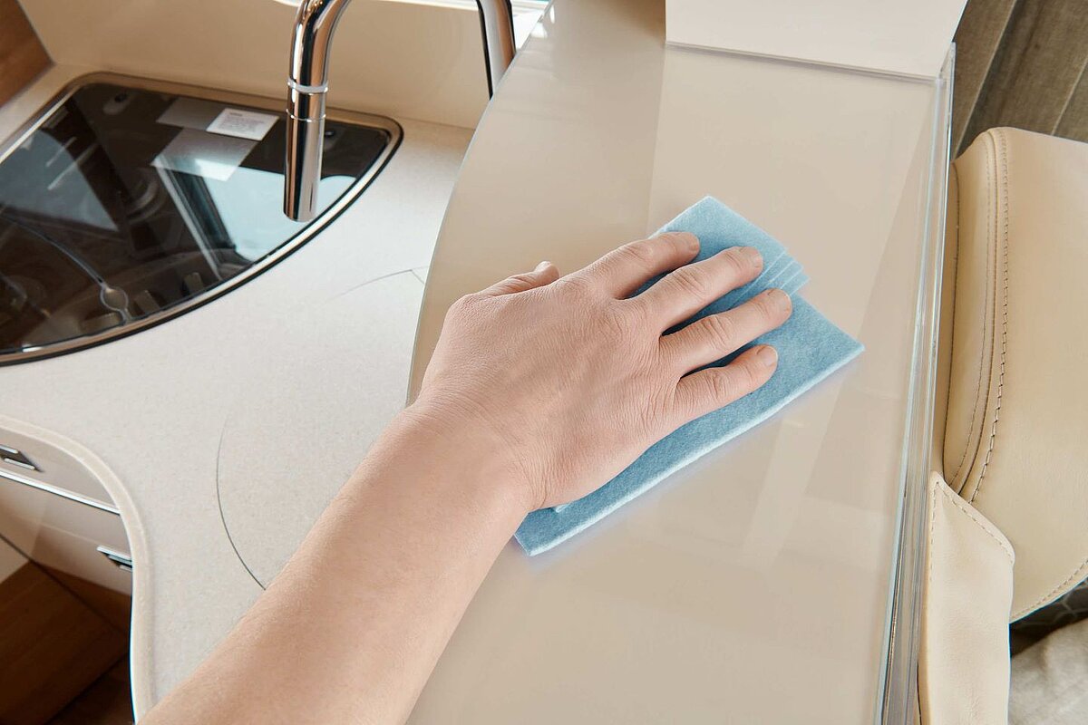 Innenansicht auf die Küche eines Carthago Wohnmobils, in welchem gerade gewischt wird