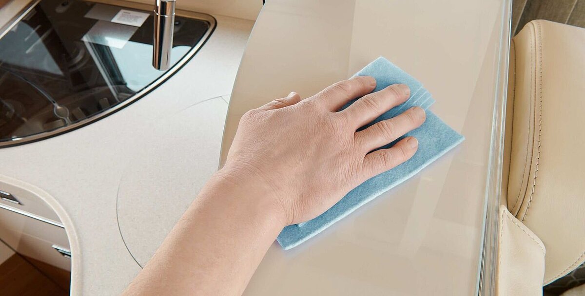 Innenansicht auf die Küche eines Carthago Wohnmobils, in welchem gerade gewischt wird