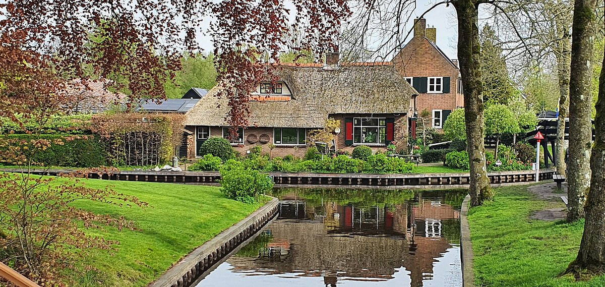 Blick auf ein niederländisches Haus mit einem Bach im Vordergrund
