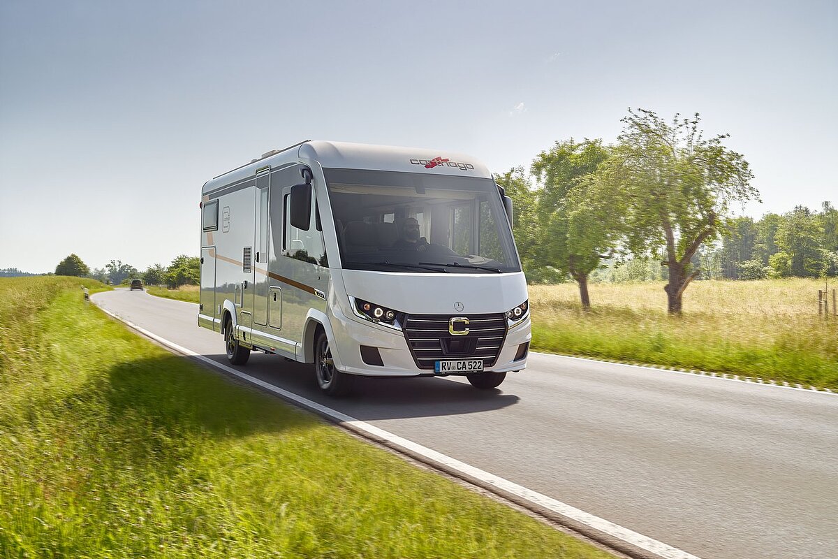 Ansicht des neuen C2-Tourers von Carthago fährt auf einer Straße zwischen Wiesen