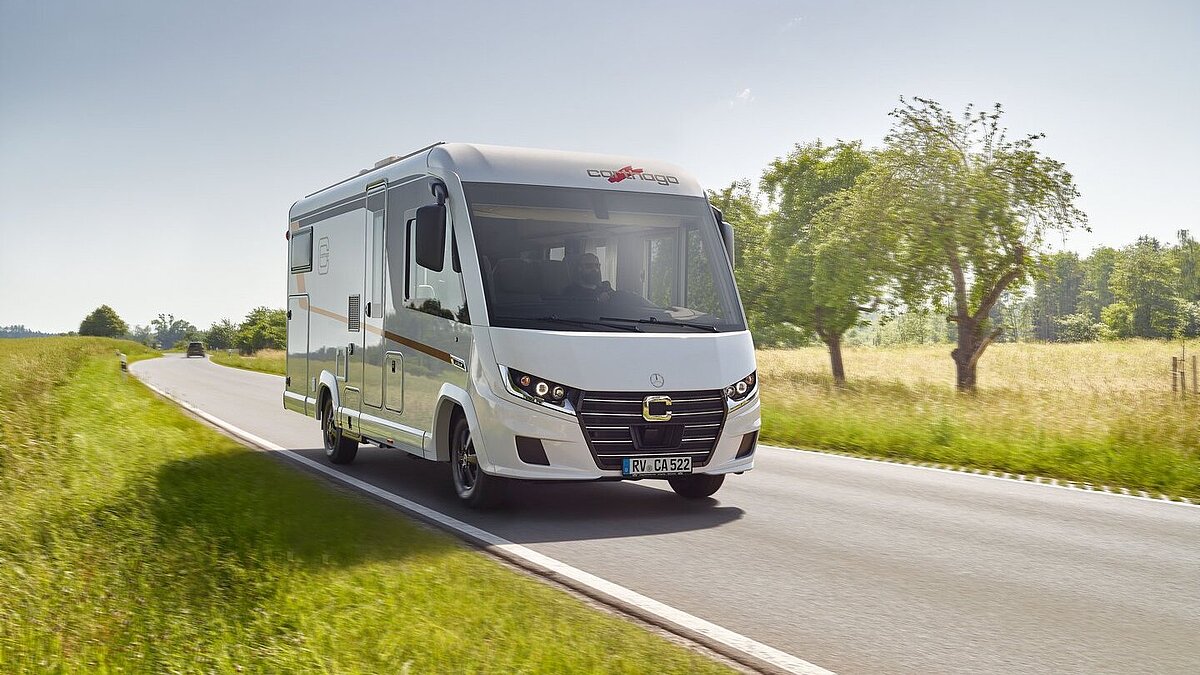 Ansicht des neuen C2-Tourers von Carthago fährt auf einer Straße zwischen Wiesen