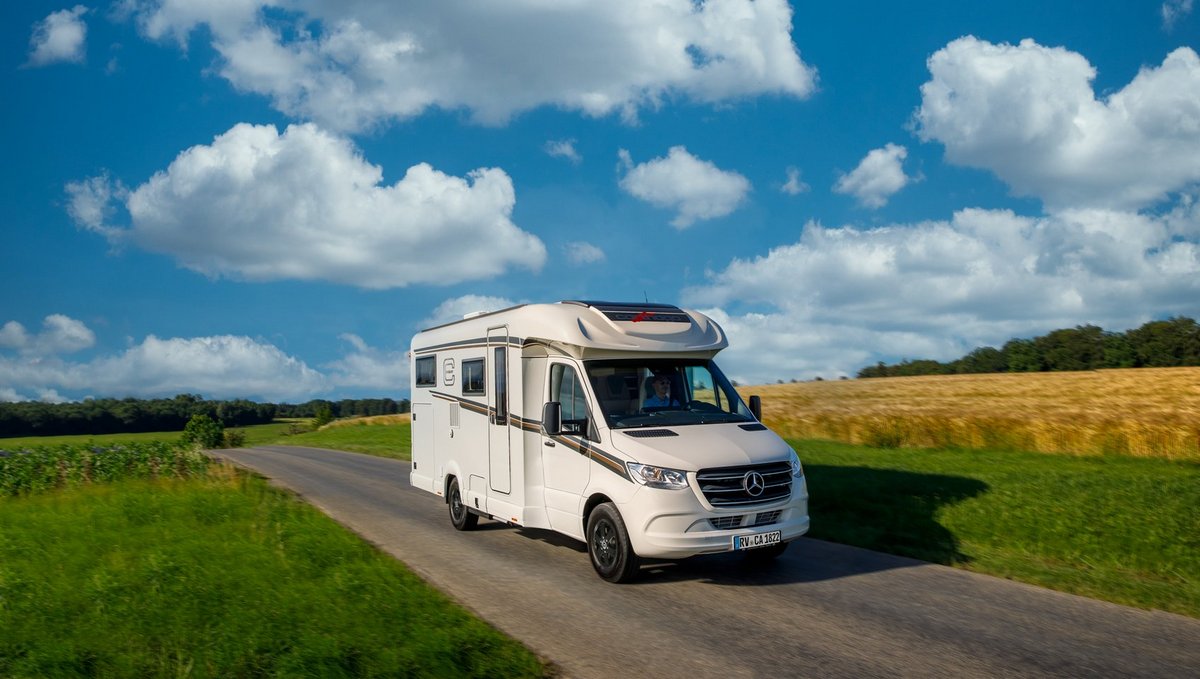 Teilintegriertes Carthago Wohnmobil c-tourer T 143 LE auf Mercedes-Benz Sprinter auf einer Straße umgeben von grüner Landschaft 