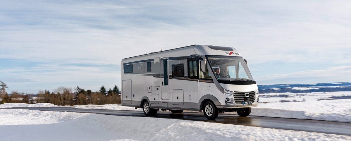 Schneelandschaft Carthago Wohnmobil s-plus fahrend auf der Straße 
