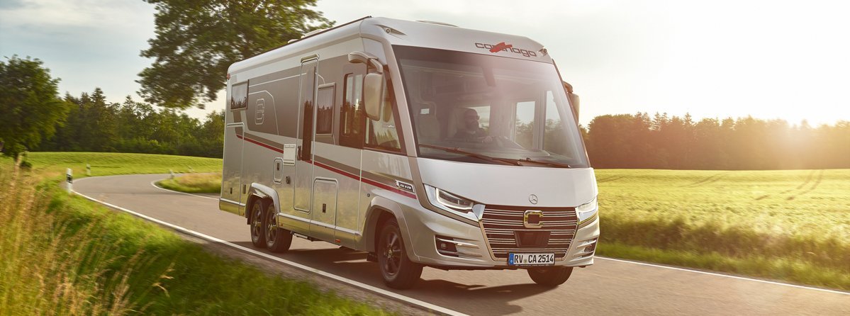 Fahraufnahme Carthago Wohnmobil e-line auf Straße mit Baum im Hintergrund