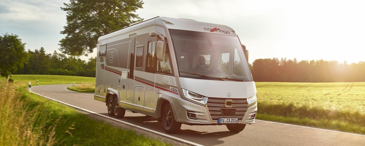 Fahraufnahme Carthago Wohnmobil e-line auf Straße mit Baum im Hintergrund