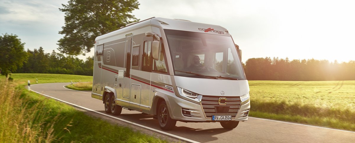 Fahraufnahme Carthago Wohnmobil e-line auf Straße mit Baum im Hintergrund
