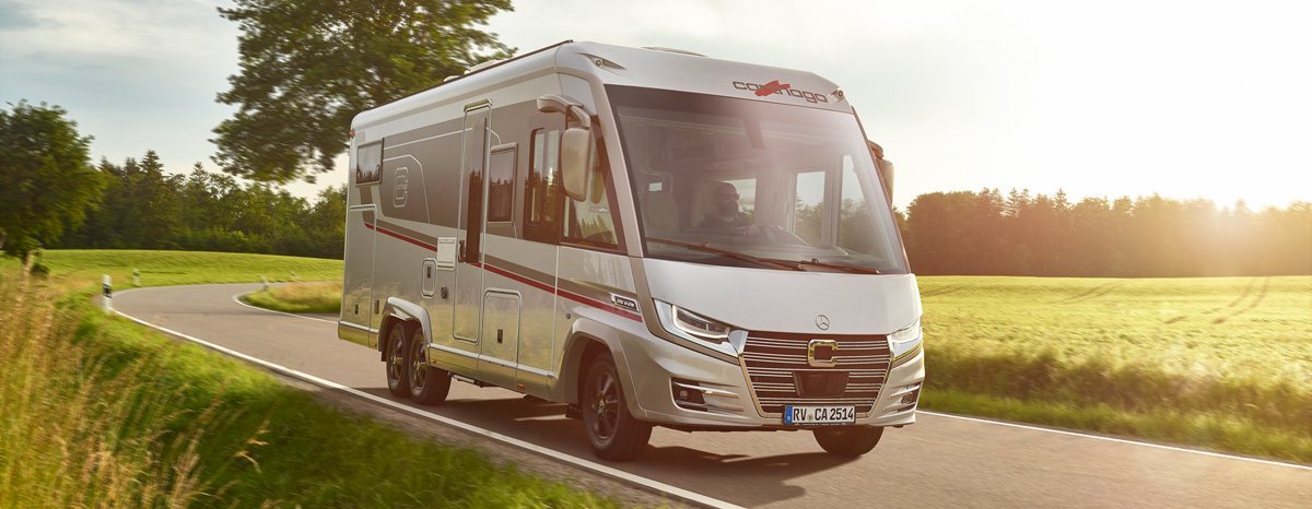 Fahraufnahme Carthago Wohnmobil e-line auf Straße mit Baum im Hintergrund