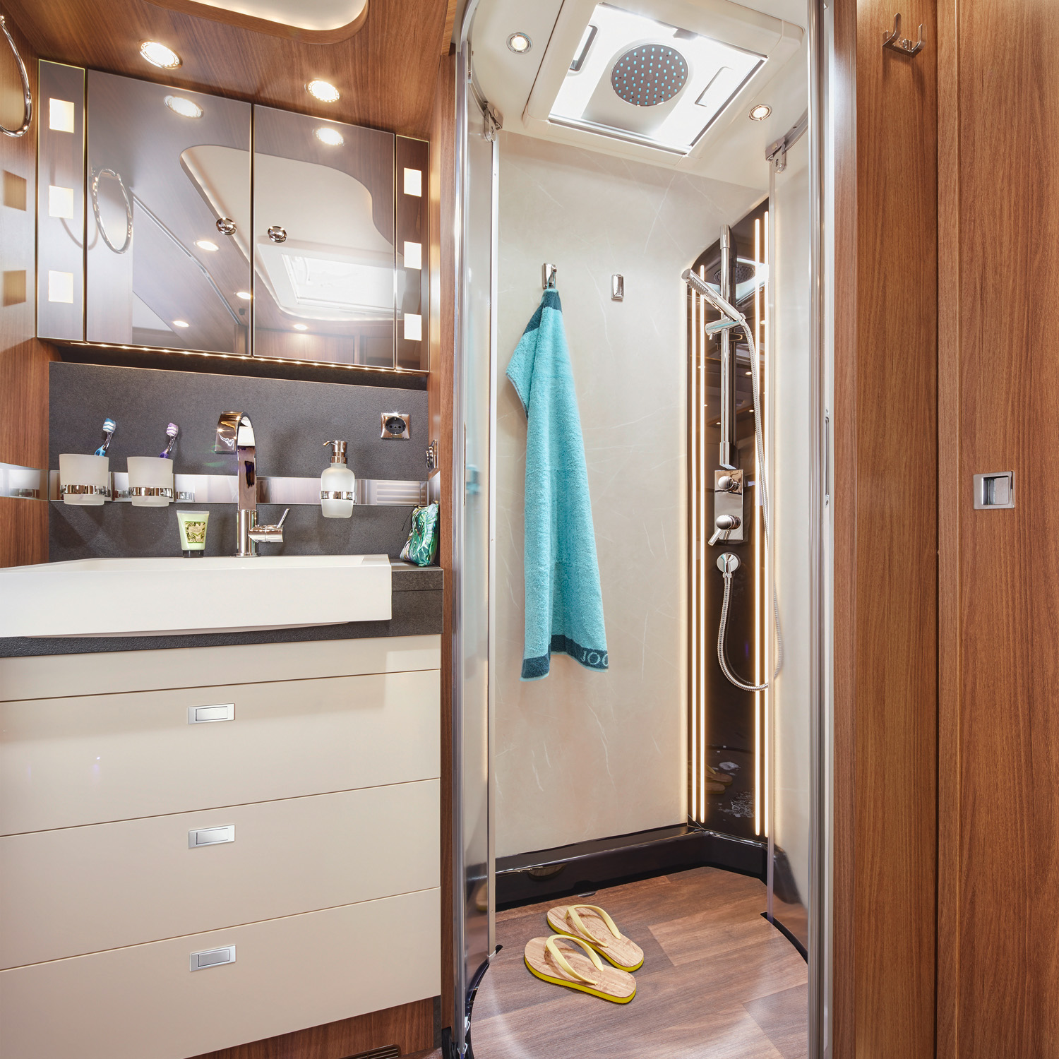 Dusche und Waschbecken im Raumbad eines Reisemobils mit Zahnputzbecher und Seifenspender
