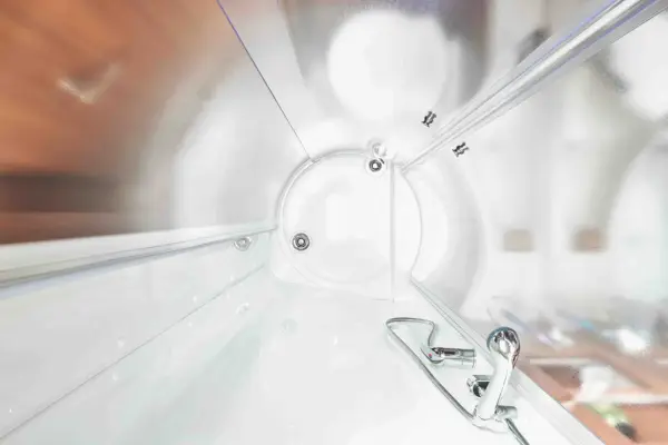 Innenansicht einer hellen, modernen hyperbaren Sauerstofftherapiekammer mit strahlend weißen Wänden und einer runden Tür - in Anlehnung an das elegante Design des Carthago C2-Tourer - mit Bedienknöpfen und Anzeigen an der Seitenwand.