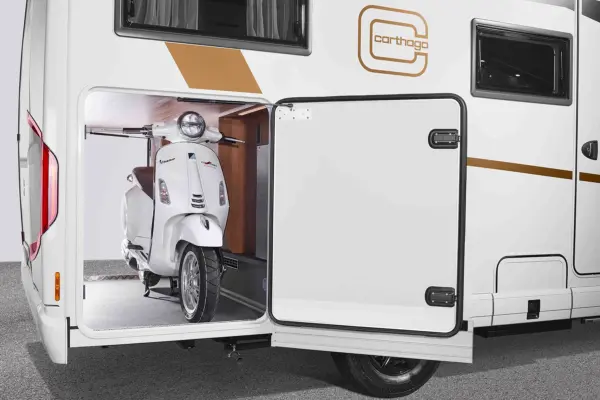 Ein weißer Roller ist sicher im Stauraum eines weißen Carthago C2-Tourer-Wohnmobils geparkt, wobei die Tür geöffnet ist und den Blick auf das geräumige Innere des Fahrzeugs freigibt.
