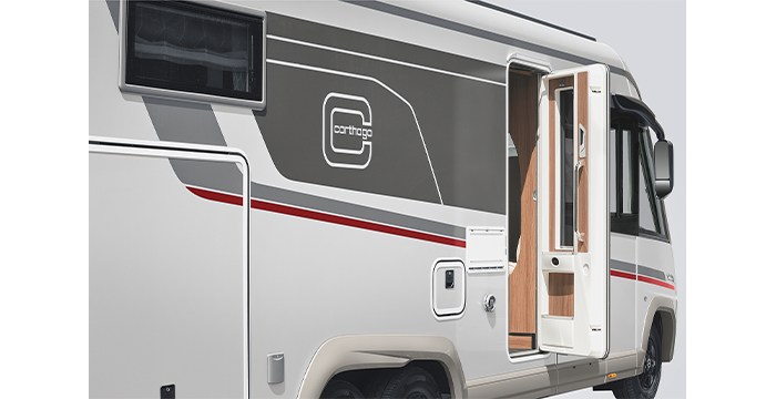 Ein weiß-graues Wohnmobil mit rotem Streifen wird von der Seite gezeigt, mit einer offenen Eingangstür, einem Fenster und dem Carthago-Logo auf der Außenseite.