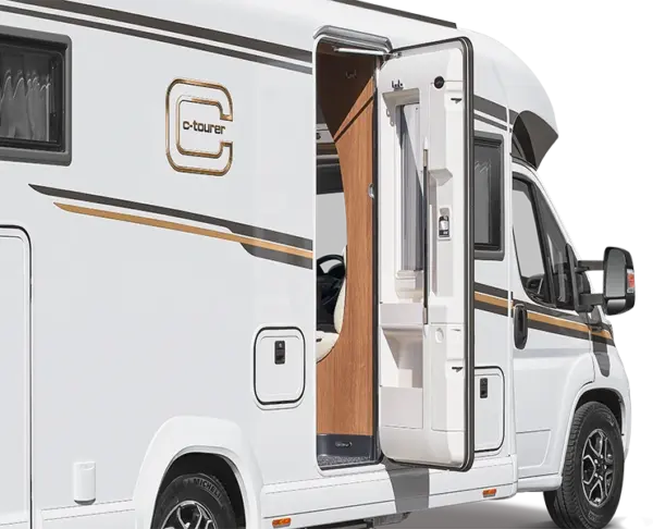 Ein weißes Wohnmobil mit goldenen und schwarzen Akzenten, das die Bezeichnung C-Tourer trägt, ist mit geöffneter Eingangstür geparkt, die einen Teil des hölzernen Innenraums und der eingebauten Ablagefächer freigibt.