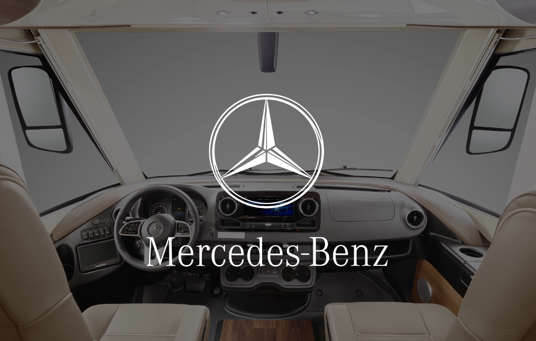 Blick in ein teilintegriertes Wohnmobil-Cockpit mit modernem Armaturenbrett und Lenkrad, in dessen Mitte das Mercedes-Benz Logo und der Name prominent eingeblendet sind.