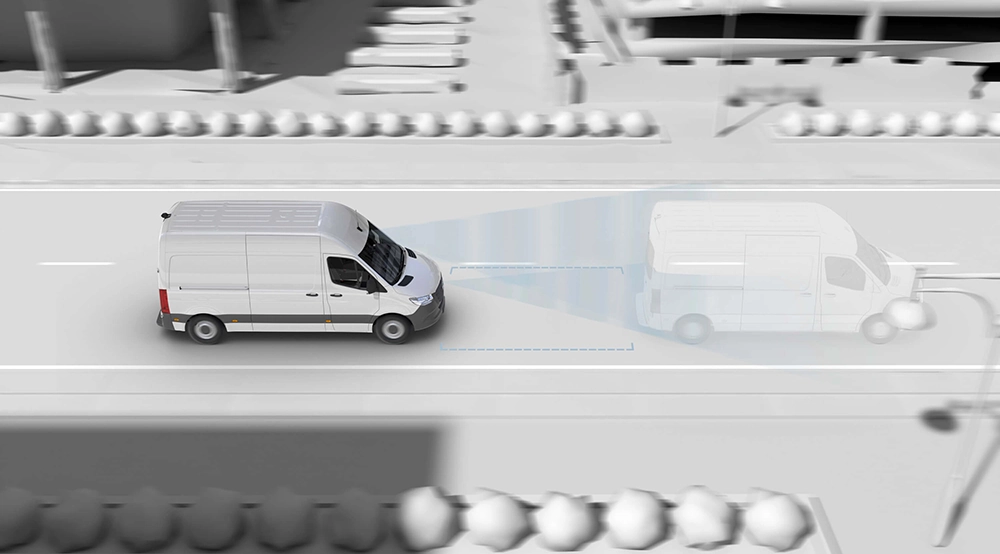A white Mercedes motorhome is travelling along an urban road, while a blue overlay illustrates the advanced driver assistance system that detects a vehicle ahead. Buildings, trees and cars can be seen in the gray scale background.