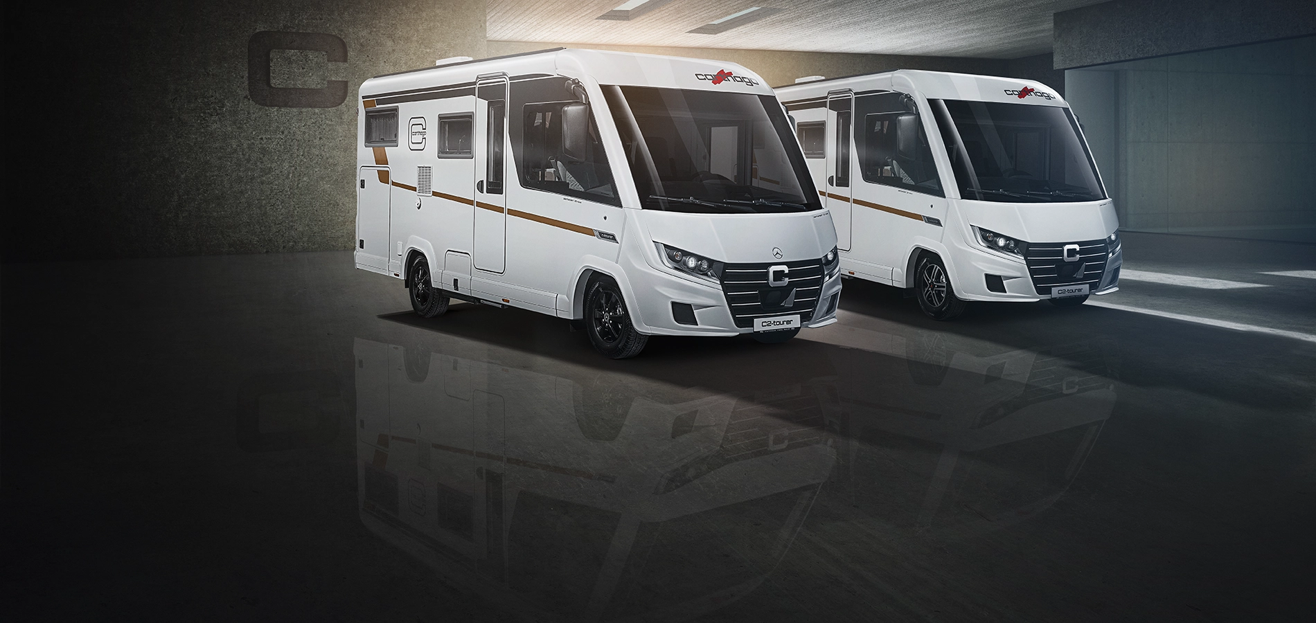 Zwei moderne weiße Wohnmobile mit schwarzen Akzenten, darunter der Carthago C2-Tourer, sind in einem Innenraum auf einem glänzenden Boden geparkt, der ihre Bilder widerspiegelt. Die Fahrzeuge haben große Frontfenster und stehen vor einer geräumigen Garage mit gedämpfter Beleuchtung.
