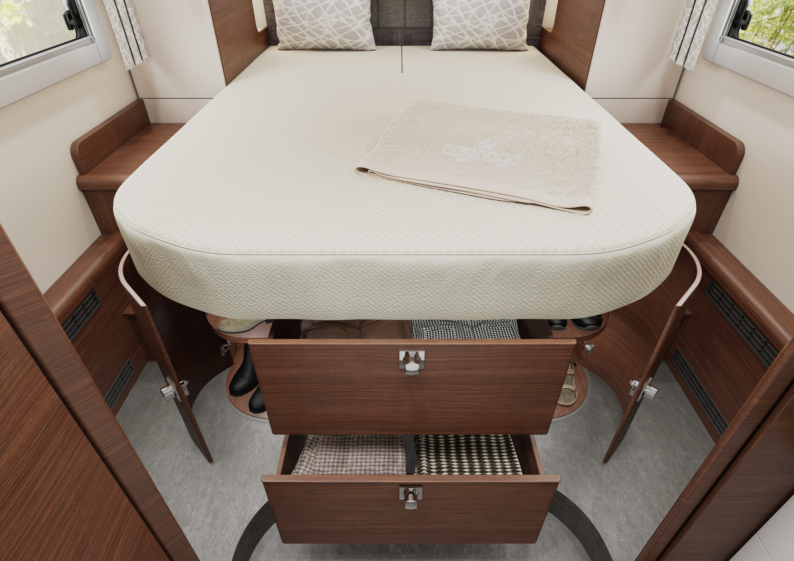 Een keurig opgemaakt bed in een compacte kamer heeft opberglades en -kasten in het houten frame eronder, met enkele lades en deuren open die schoenen en manden onthullen. Een opgevouwen beige handdoek ligt bovenop het bed.