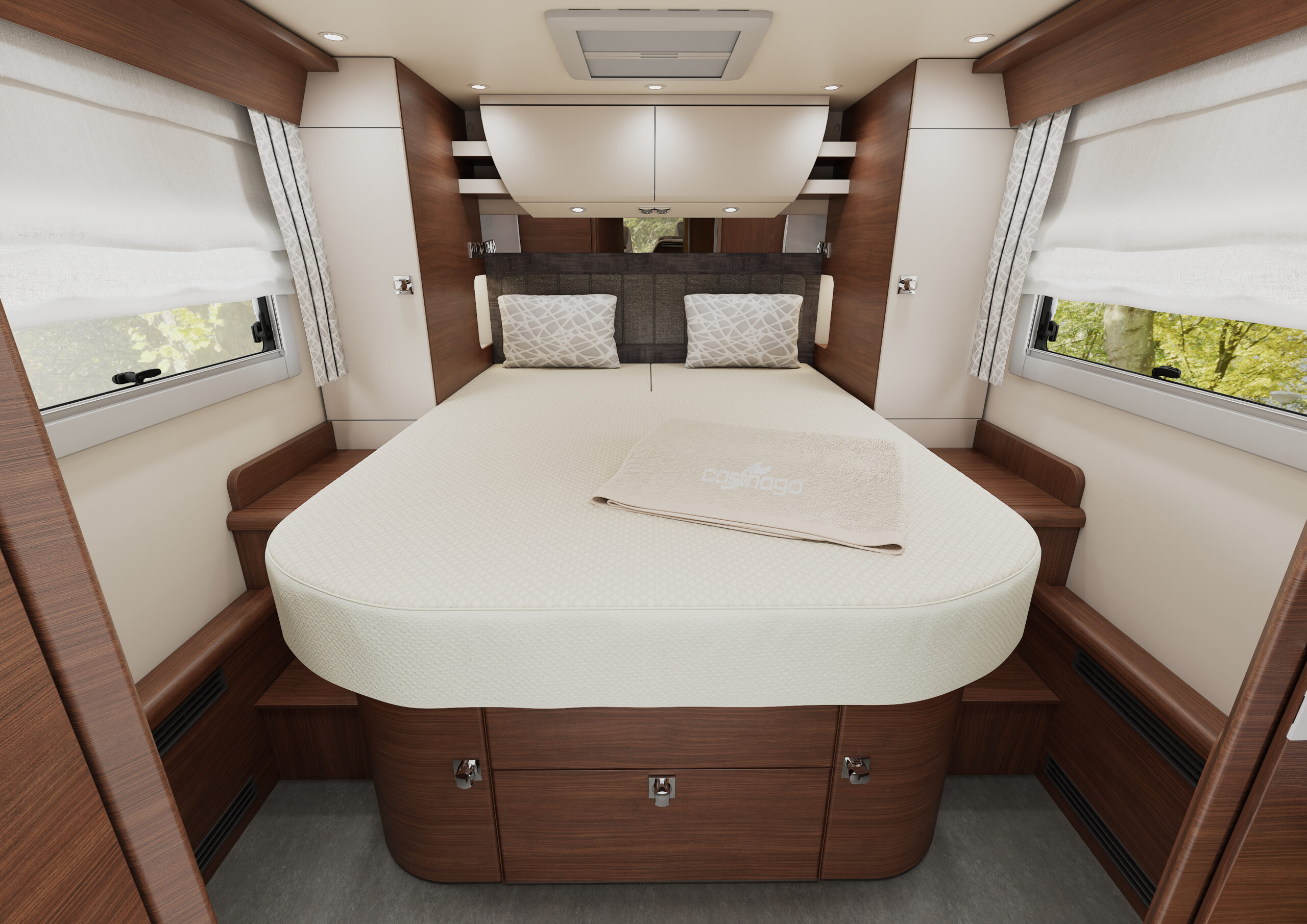 Ein ordentlich gemachtes Doppelbett mit zwei Kissen und einer gefalteten beigen Decke steht in einem gemütlichen, holzgetäfelten Wohnmobil-Schlafzimmer, umgeben von Fenstern mit weißen Vorhängen und Schubladen unter dem Bett.