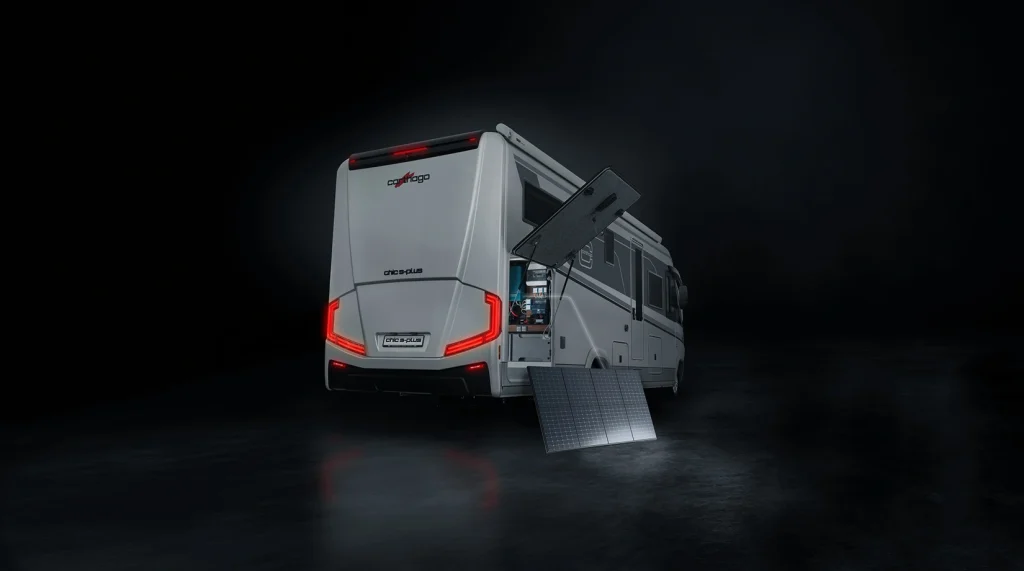Ein weißes Wohnmobil mit roten Rückleuchten steht auf einem dunklen Untergrund. Ein Seitenfach ist geöffnet und gibt den Blick auf ein am Wohnmobil befestigtes Solarpanel frei; ein weiteres Panel lehnt auf dem Boden.