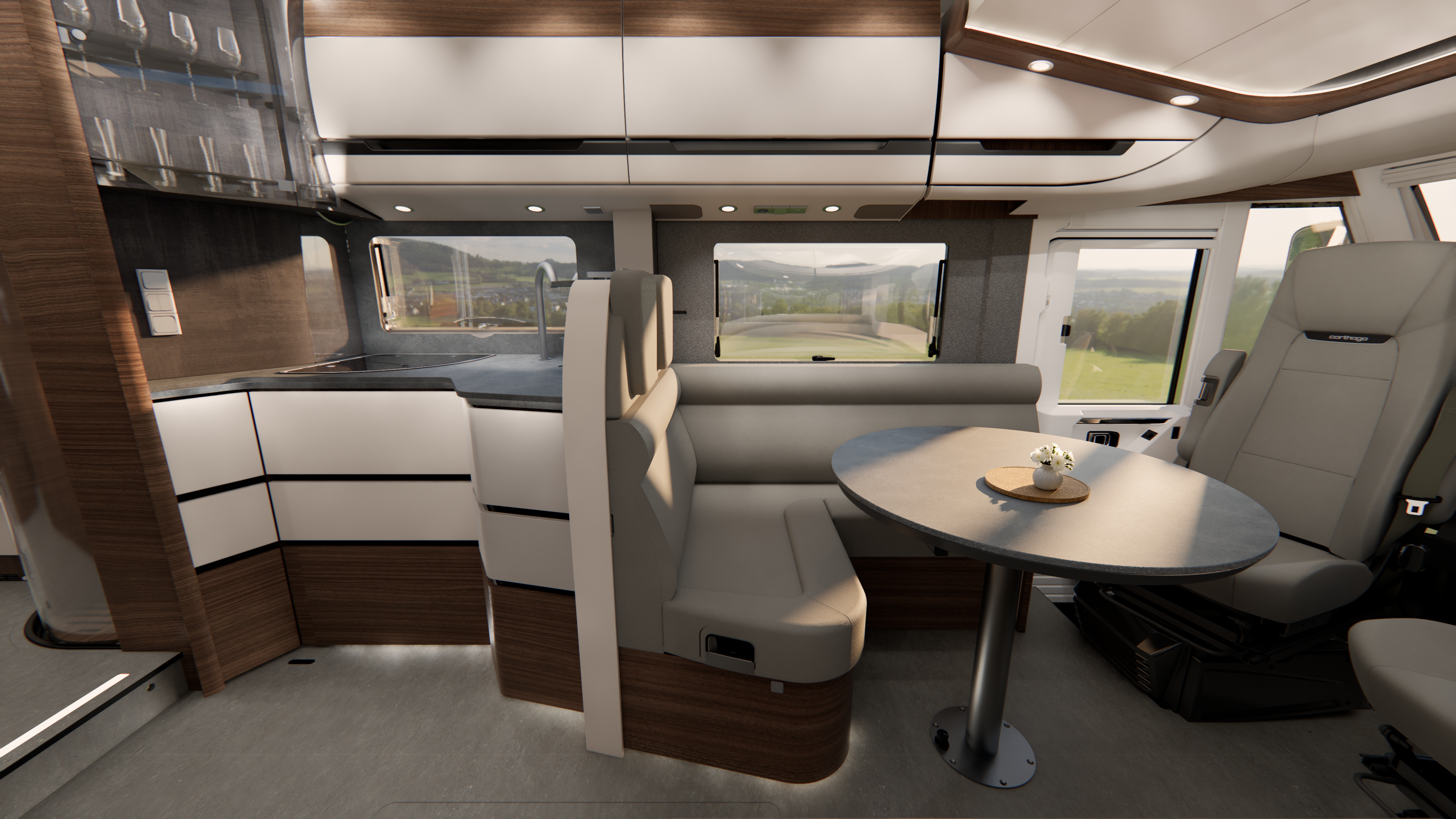 Moderne Wohnmobil-Innenausstattung mit Holz- und weißen Oberflächen, einem runden Tisch mit einer Blume, gepolsterten Sitzgelegenheiten, einem Küchenbereich und großen Fenstern, die einen malerischen Blick ins Freie bieten.