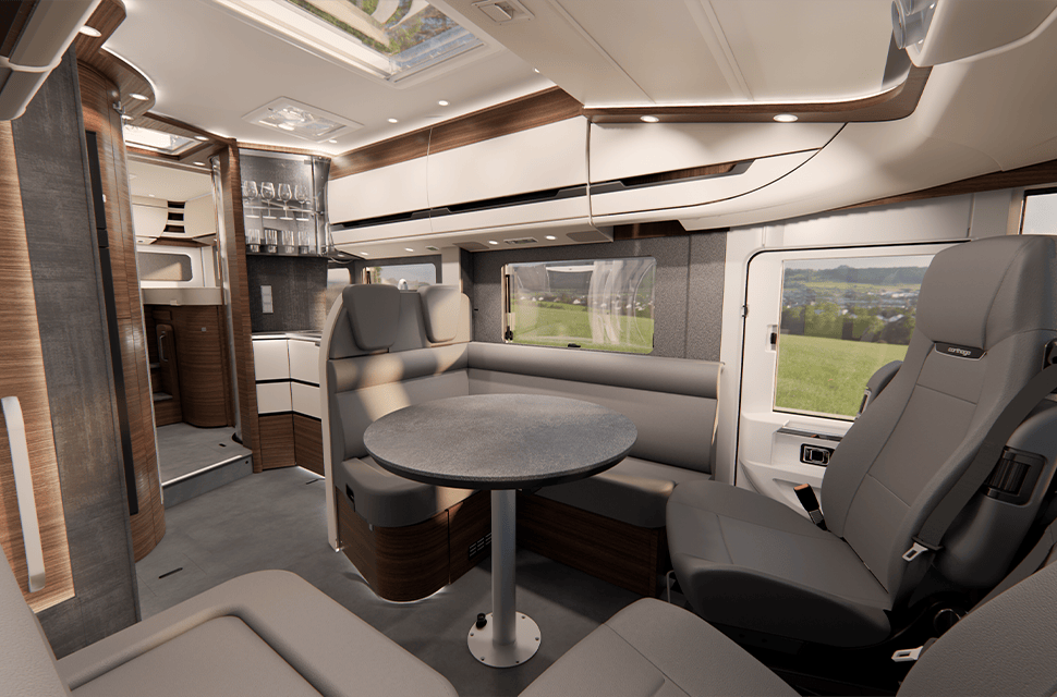 Moderner Wohnmobil-Innenraum mit einem Essbereich, der aus einem runden Tisch, gepolsterten Sitzgelegenheiten, großen Fenstern mit malerischem Ausblick und Schränken in neutralen Farbtönen besteht.