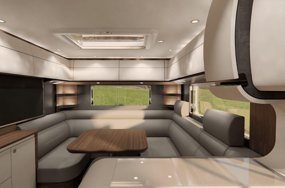 Moderne Wohnmobil-Innenausstattung mit cremefarbenen Schränken, großen Fenstern, einem L-förmigen Sofa, einem Holztisch und Einbauleuchten. Der Raum wirkt hell und einladend, und vor den Fenstern ist grünes Gras zu sehen.