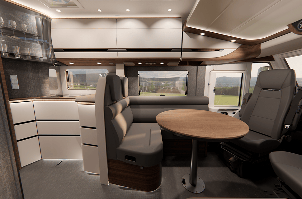 Moderne Wohnmobil-Innenausstattung mit einem runden Holztisch, gepolsterten Sitznischen, einem Drehstuhl, Einbauschränken und großen Fenstern, die einen malerischen Blick nach draußen bieten.
