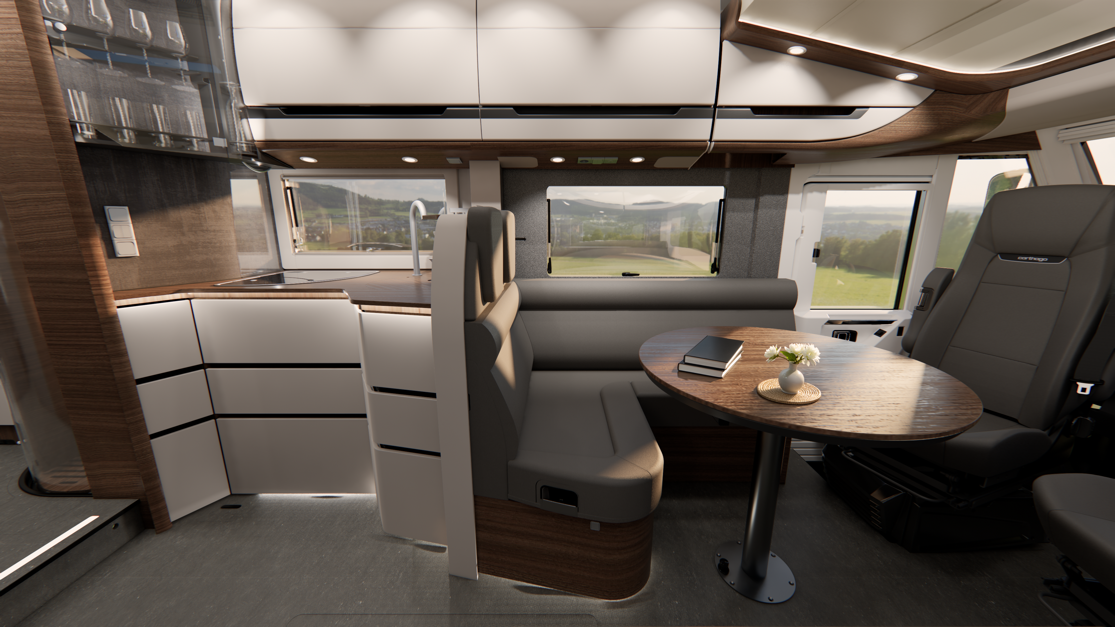 Moderner Wohnmobil-Innenraum mit Holzakzenten, einem runden Tisch, einer kompakten Küche, zwei Stühlen, einer Sofabank und großen Fenstern, die einen malerischen Blick ins Freie bieten. Auf dem Tisch liegen ein Buch und eine kleine Blumenvase.
