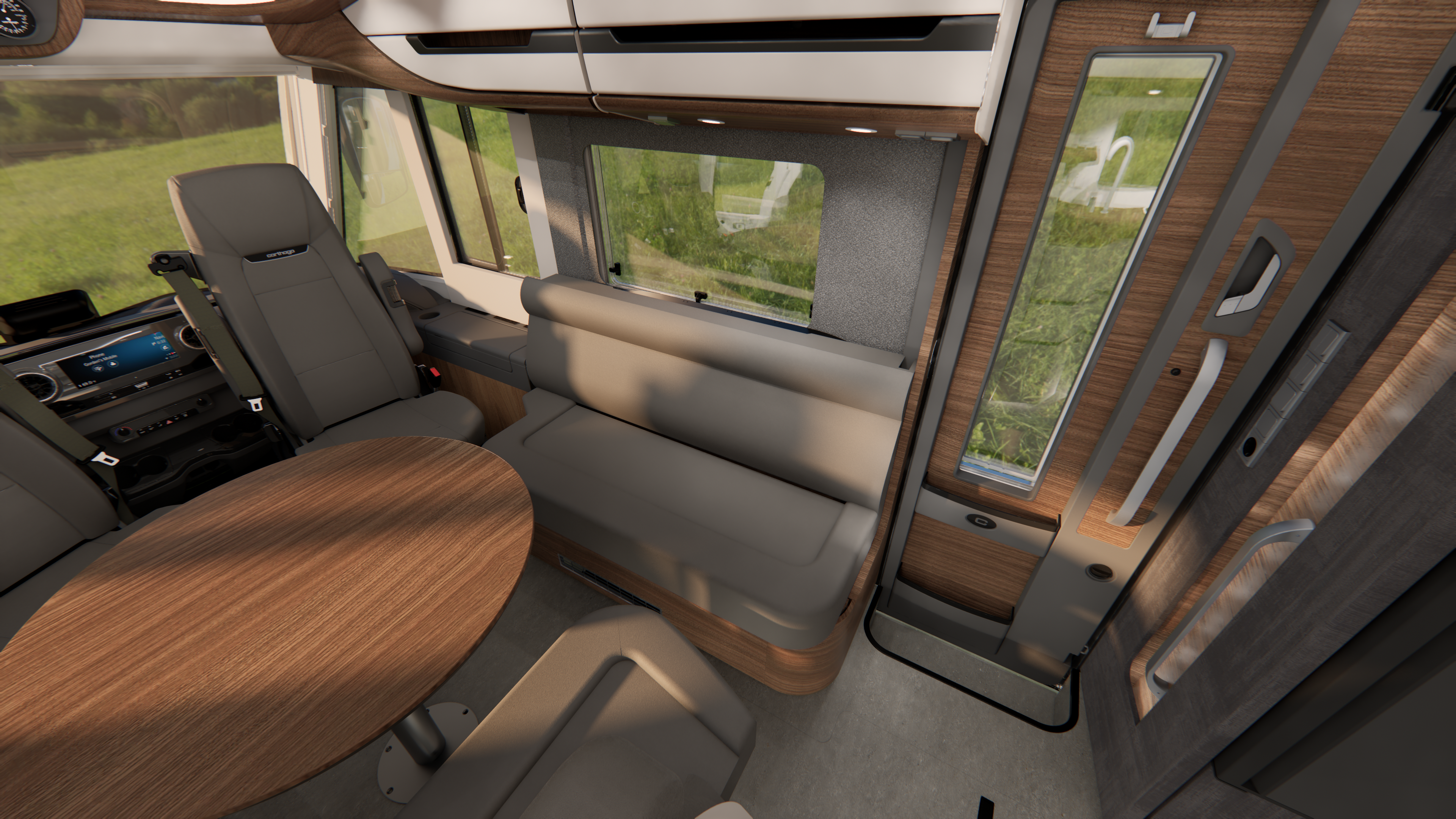 Innenansicht eines modernen Wohnmobils mit einem grauen Sofa, einem runden Holztisch, einem Kapitänsstuhl und großen Fenstern, durch die man die grüne Landschaft draußen sehen kann. Holzvertäfelungen und elegante Designelemente sind zu sehen.