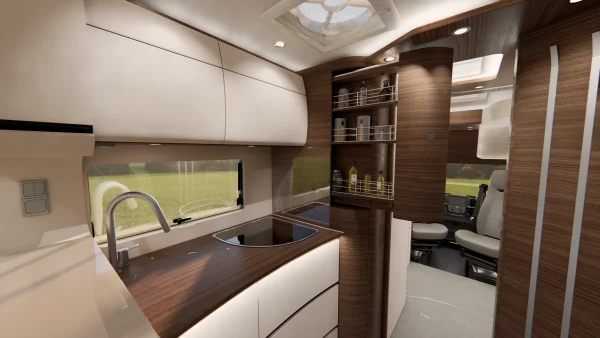 Moderne Wohnmobilküche mit eleganten Holz- und weißen Schränken, einer Spüle, einem Herd, Einbauregalen für verschiedene Gegenstände und einem Fenster, durch das man das grüne Gras draußen sehen kann. Im Hintergrund ist der Fahrersitz zu sehen, der das elegante Design des Carthago Liner for Two unterstreicht.