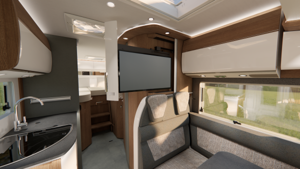 Innenraum eines modernen Carthago C2-Tourer-Wohnmobils mit Küchenbereich, Spüle, Sitzgelegenheiten, einem darüber angebrachten Fernseher und großen Fenstern, durch die Tageslicht hereinströmt. Im Hintergrund sind eine Treppe und ein Bett zu sehen.
