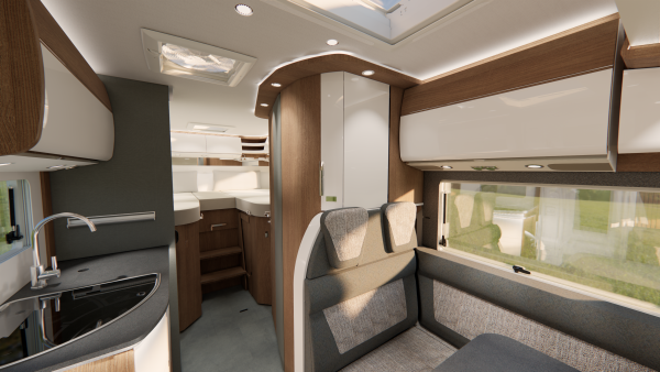 Ein modernes Wohnmobil-Interieur mit Holzakzenten, einer kompakten Küche mit Spüle und Herd, einer Essecke, Stauraum an der Decke und einem Blick auf den Schlafbereich im hinteren Teil bei natürlichem Licht – dieser Carthago c2-Tourer vereint Komfort und Stil für Reisende, die ein erstklassiges Erlebnis auf der Straße suchen.