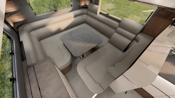 Der Innenraum eines modernen Carthago Liner-for-Two-Wohnmobils mit einer U-förmigen Sitzgruppe aus beigem Leder rund um einen grauen, rechteckigen Tisch, großen Fenstern und grünem Gras, das draußen zu sehen ist.
