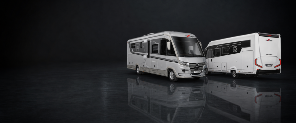 Zwei moderne weiße Carthago Chic S Plus-Wohnmobile mit roten und schwarzen Akzenten stehen auf einer reflektierenden dunklen Fläche, leicht zueinander hin ausgerichtet, vor einem schlichten dunklen Hintergrund.