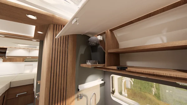 Innenraum eines modernen Carthago C2-Tourer-Wohnmobils mit offenen Holzschränken, Regalen, einem kleinen Waschbecken und einem Fenster, durch das man die grüne Landschaft draußen sehen kann. Sanfte Beleuchtung und neutrale Farben sorgen für eine gemütliche Atmosphäre.