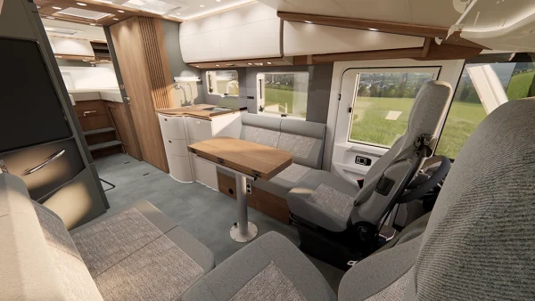Innenraum eines modernen Carthago C2-Tourer-Wohnmobils mit hellen Holzmöbeln, grauen Sitzgelegenheiten, einem drehbaren Fahrersitz, einem Esstisch, einer Küchenzeile und großen Fenstern mit Blick auf eine grüne Landschaft.