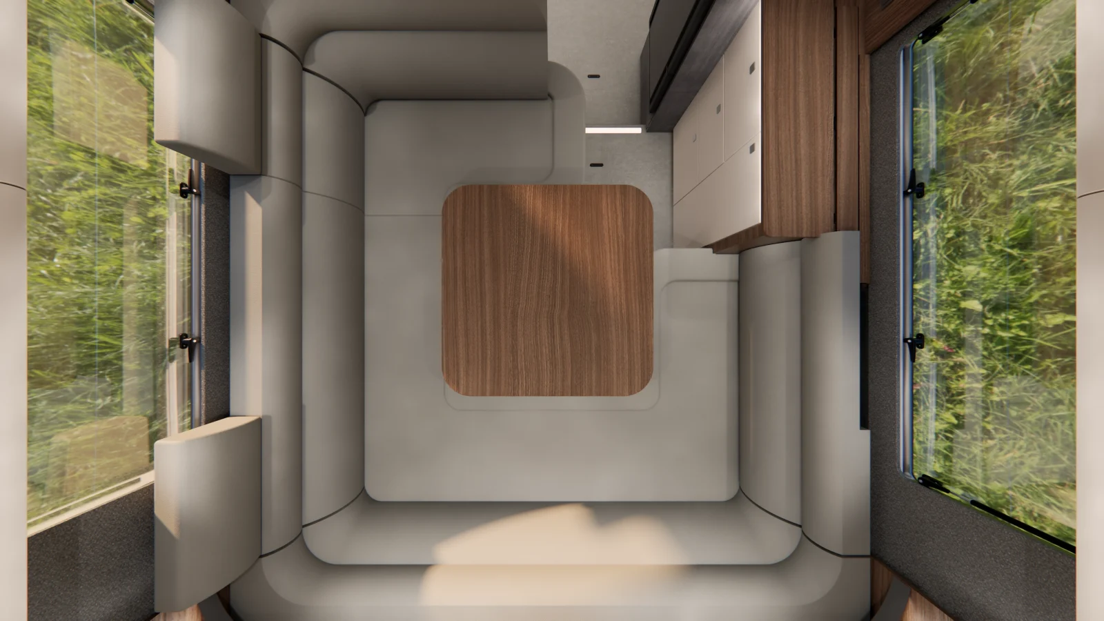 Draufsicht auf den Innenraum eines modernen, minimalistischen Carthago Liner for Two-Wohnmobils mit hellgrauen Polstersitzgelegenheiten, die einen quadratischen Holztisch umgeben, Holzschränken und einem Fenster, durch das man das Grün draußen sehen kann.