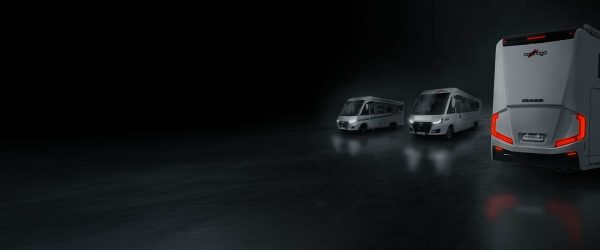 Tre camper moderni con luci posteriori accese procedono su una superficie scura e riflettente, spostandosi da destra a sinistra; il camper più grande è in primo piano, mentre i due più piccoli si trovano sullo sfondo.