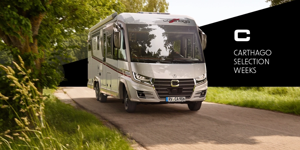 Ein silbernes Carthago-Wohnmobil fährt eine von Bäumen gesäumte Landstraße entlang. Auf der rechten Seite ist auf einem schwarzen Banner die Aufschrift „Carthago Selection Weeks“ mit einem stilisierten C-Logo zu sehen.