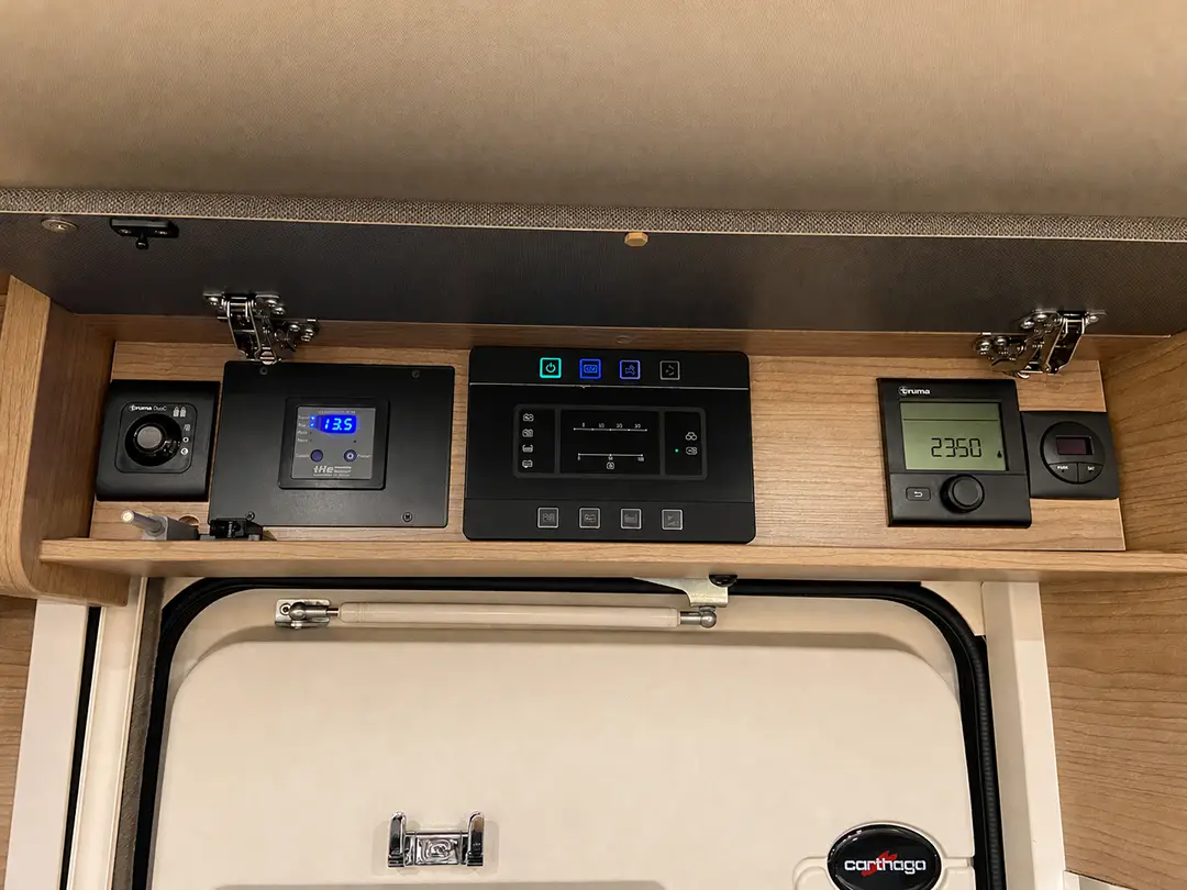 Bedienfeld für einen Carthago C2-Tourer-Wohnmobil mit digitalen Anzeigen, Schaltern und einer Truma-Heizungssteuerung oberhalb der Eingangstür.