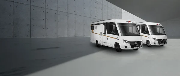 Zwei weiße Carthago-Wohnmobile, die auf einem Platz aus Architekturbeton geparkt sind.