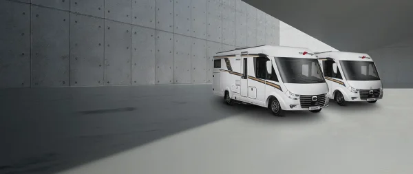 Zwei weiße Carthago-Wohnmobile standen nebeneinander auf einem modernen Betonplatz.