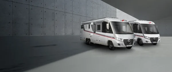 Zwei Wohnmobile der Baureihe Carthago chic c-line stehen nebeneinander in einem modernen Betonbau.